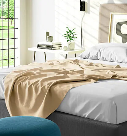 Beige bedsheet spread over a white mattress in a modern bedroom setting